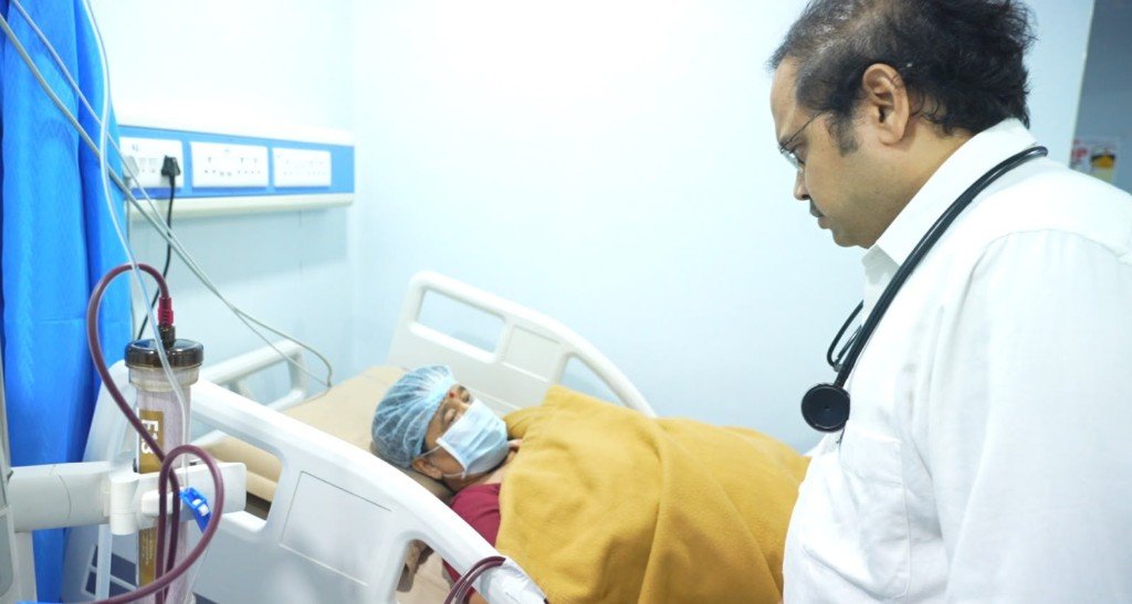 Doctor with stethoscope checking on a patient in hospital bed